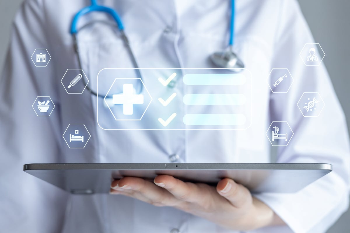 A health worker holds a tablet while checking medical information. The scene shows digital icons related to health and care technology.